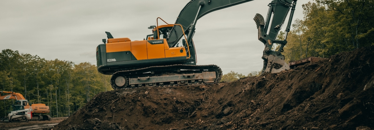 orange and white excavator on brown ground during daytime